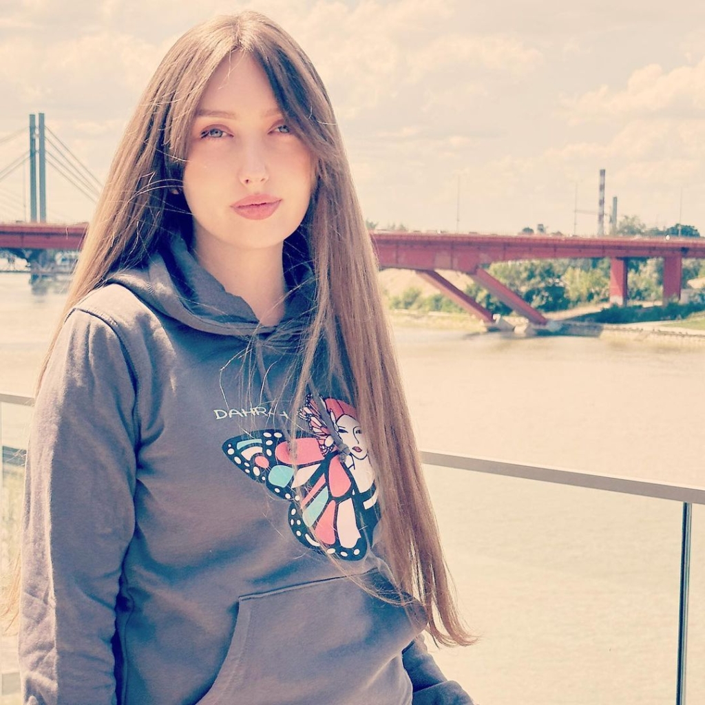 Beautiful blond girl with long hair wearing grey organic hoodie with print of a butterfly and geisha designed by Dahrah Darah Fashion.